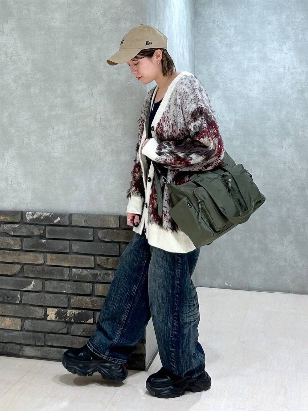 ブラック系のスニーカー、グリーン系のボストンバッグ、ホワイト系のカーディガン/ボレロを着用したレディースの秋コーディネートの5枚目の写真