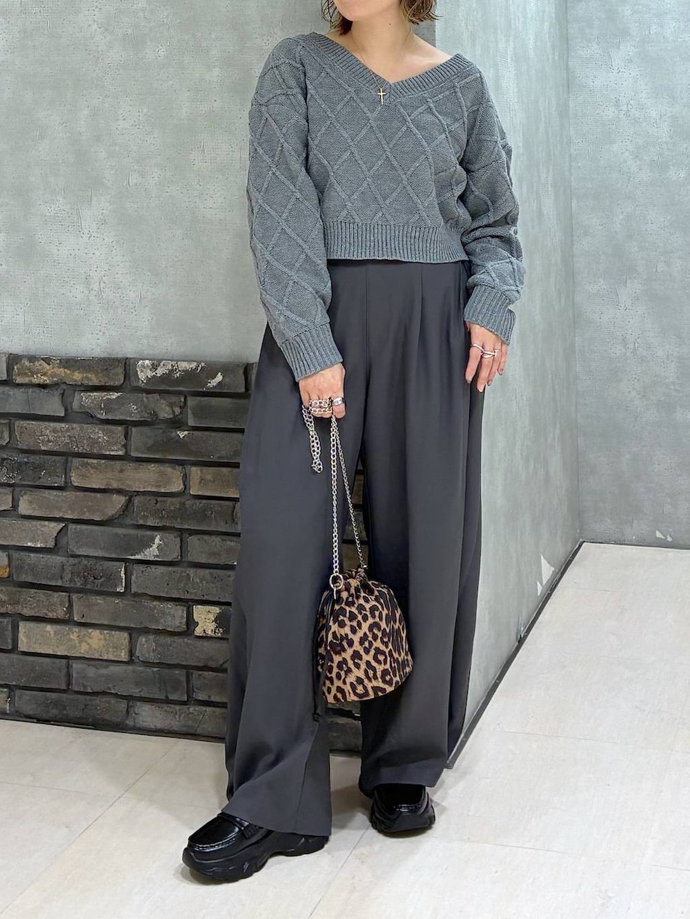 グレー系のスラックス、グレー系のニット/セーター、その他のハンドバッグを着用したレディースの秋コーディネートの2枚目の写真