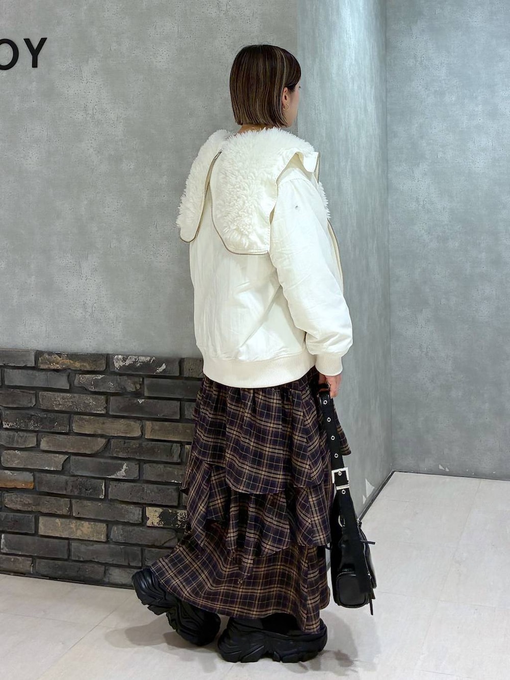 ブラック系のブーツ、ホワイト系のブルゾン、ブラウン系のスカートを着用したレディースの冬コーディネートの3枚目の写真