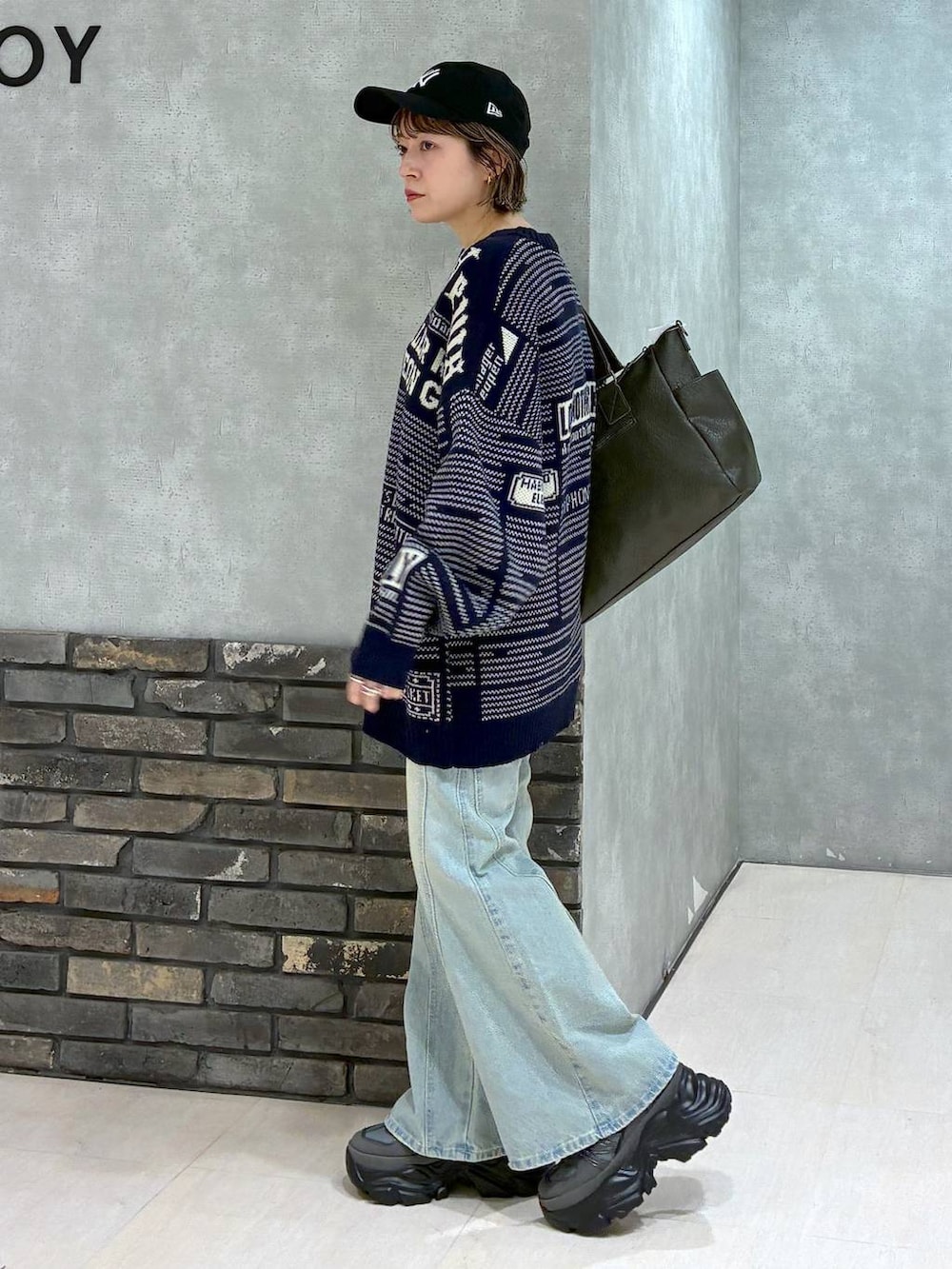 グレー系のスニーカー、ブルー系のデニムパンツ、グリーン系のボストンバッグを着用したレディースの冬コーディネートの6枚目の写真