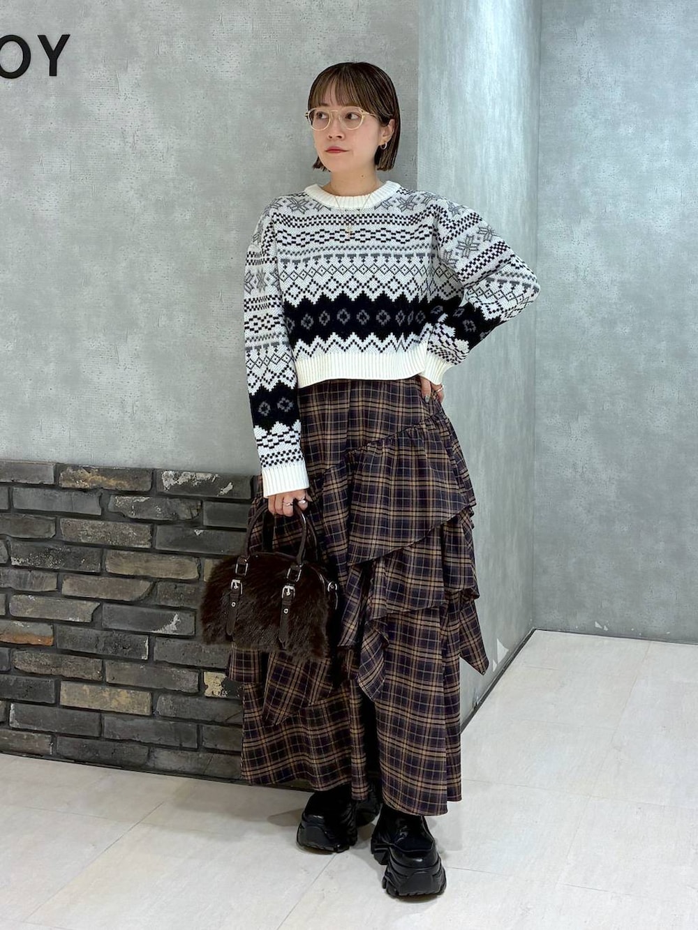 ブラック系のブーツ、ブラウン系のスカート、ブラウン系のボストンバッグを着用したレディースの冬コーディネートの2枚目の写真