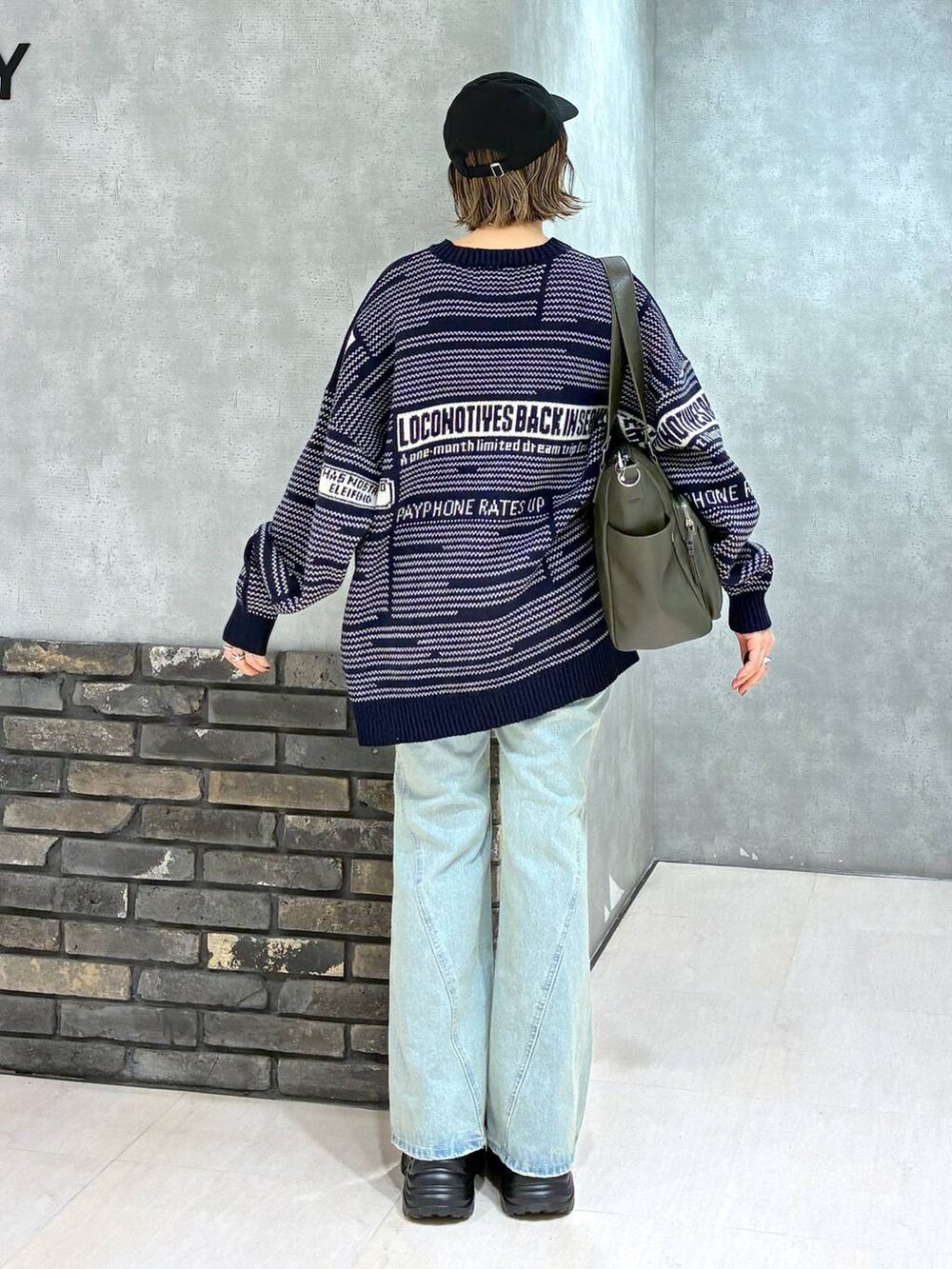 グレー系のスニーカー、ブルー系のデニムパンツ、グリーン系のボストンバッグを着用したレディースの冬コーディネートの4枚目の写真