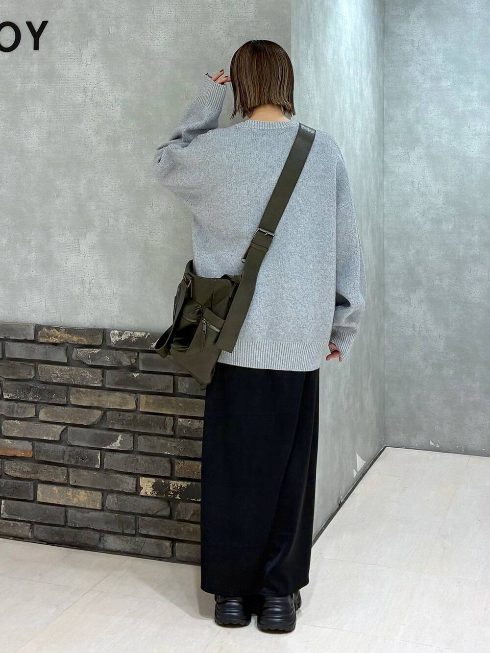 グレー系のスニーカー、グリーン系のボストンバッグ、グレー系のニット/セーターを着用したレディースの冬コーディネートの3枚目の写真