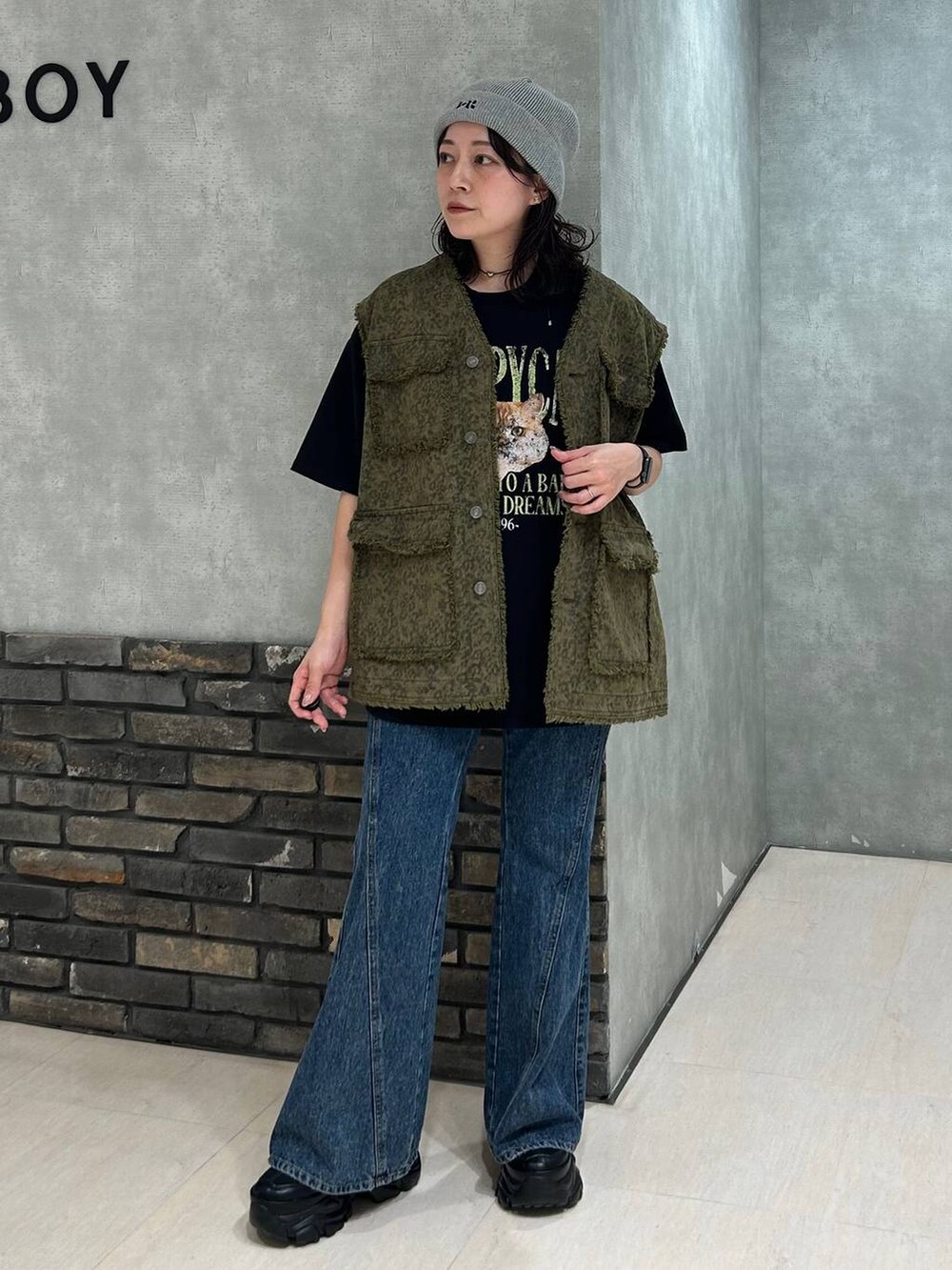 ブラック系のスニーカー、ブラック系のTシャツ/カットソー、ブルー系のデニムパンツを着用したレディースの秋コーディネートの2枚目の写真