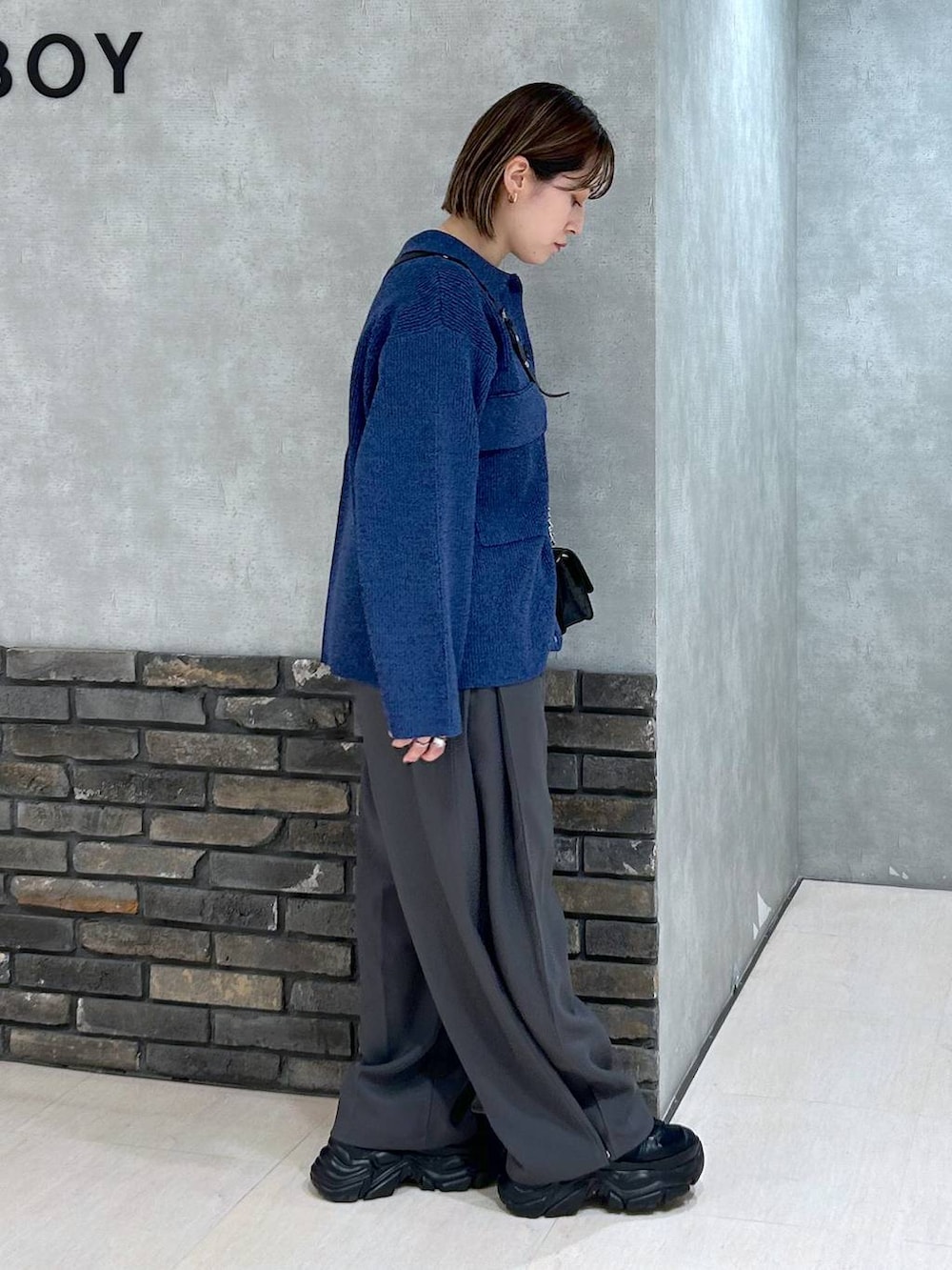 ブラック系のスニーカー、ブラック系のハンドバッグ、ブルー系のブルゾンを着用したレディースの秋コーディネートの2枚目の写真