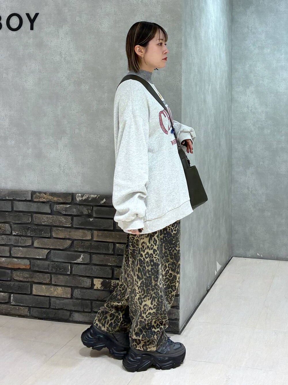 グレー系のスニーカー、グリーン系のボストンバッグ、ベージュ系のスウェットを着用したレディースの冬コーディネートの2枚目の写真