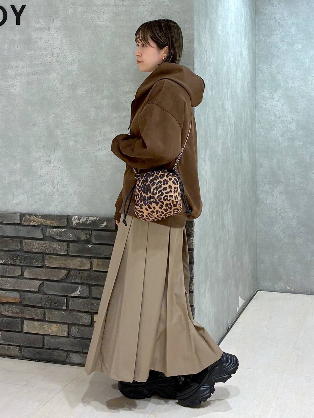 ブラック系のブーツ、ブラウン系のパーカー、ベージュ系のスカートを着用したレディースの冬コーディネートの6枚目の写真