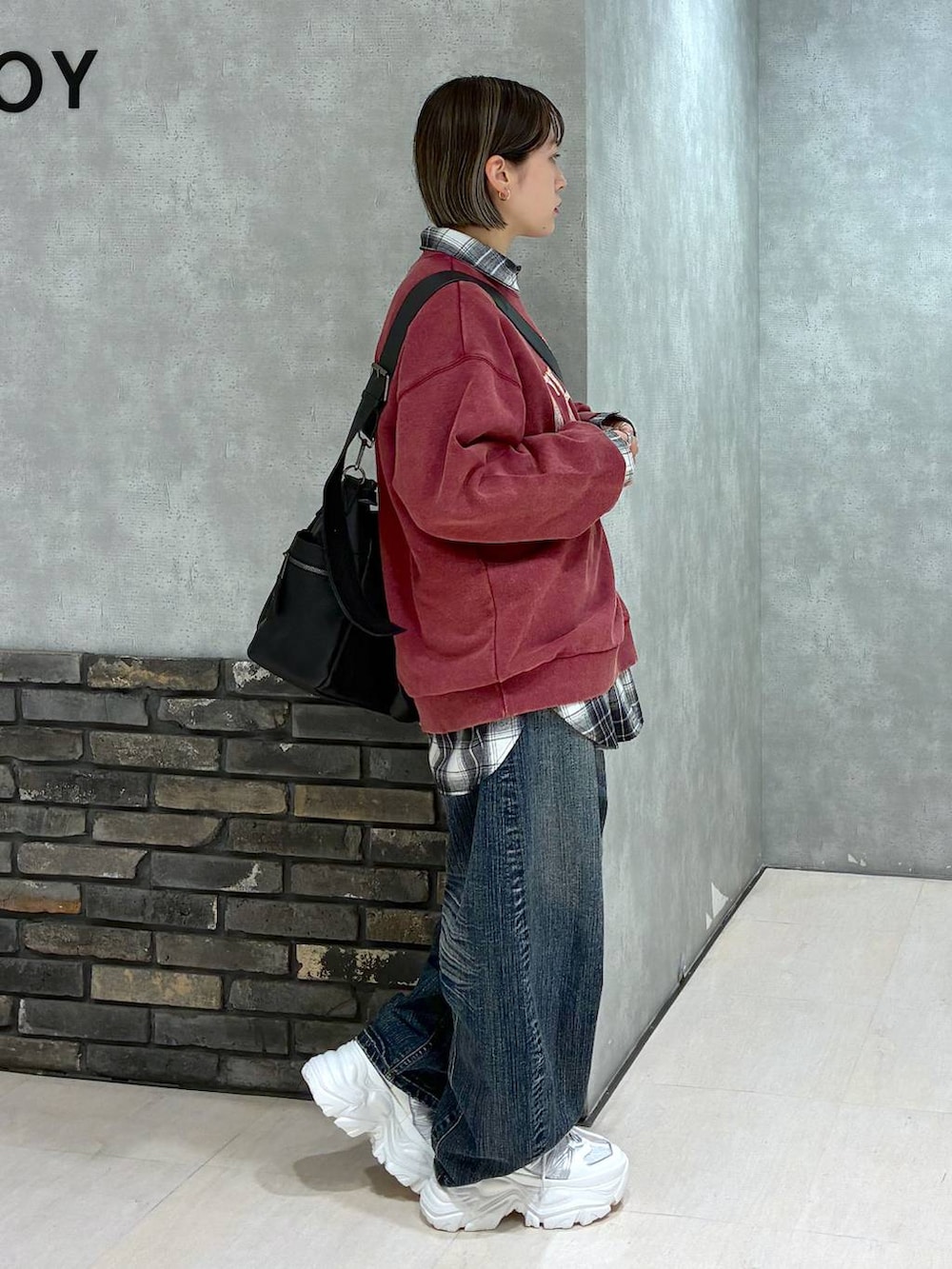 ホワイト系のスニーカー、ブラック系のボストンバッグ、レッド系のスウェットを着用したレディースの冬コーディネートの2枚目の写真