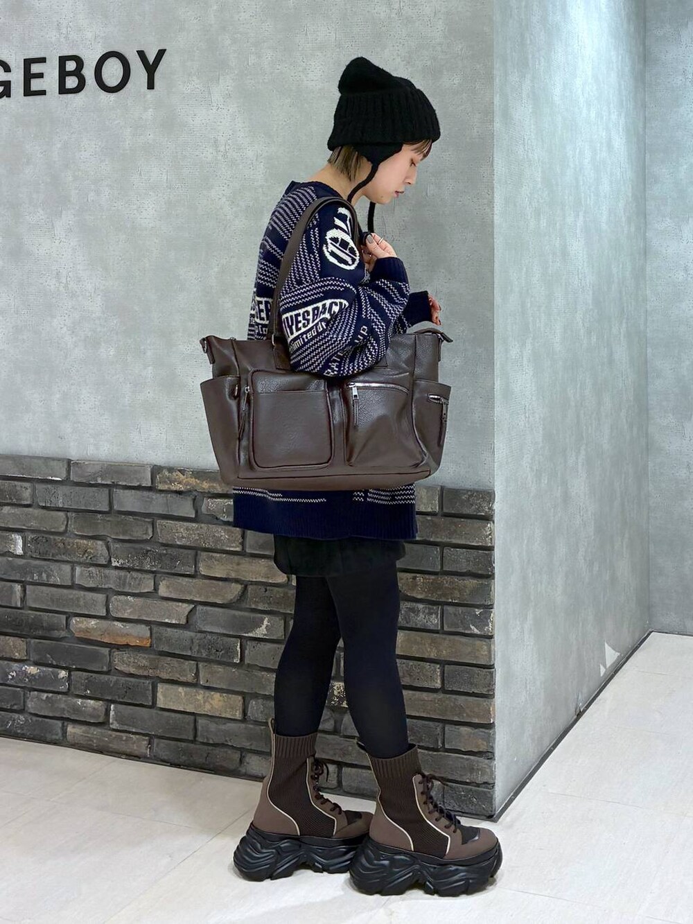 ブラウン系のブーツ、ブラウン系のボストンバッグ、ブラック系のスカートを着用したレディースの冬コーディネートの3枚目の写真