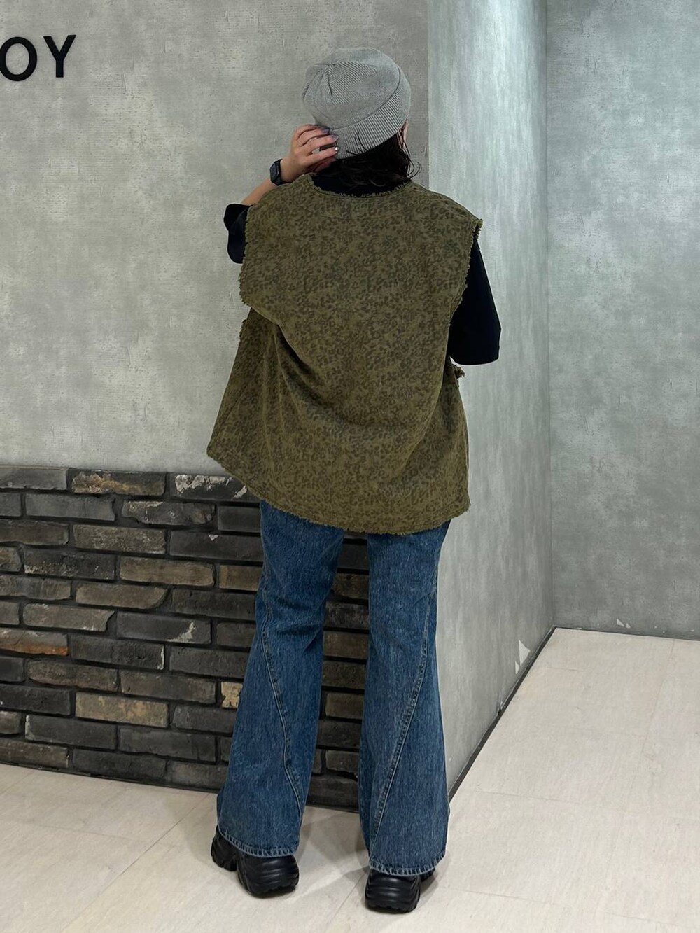 ブラック系のスニーカー、ブラック系のTシャツ/カットソー、ブルー系のデニムパンツを着用したレディースの秋コーディネートの4枚目の写真