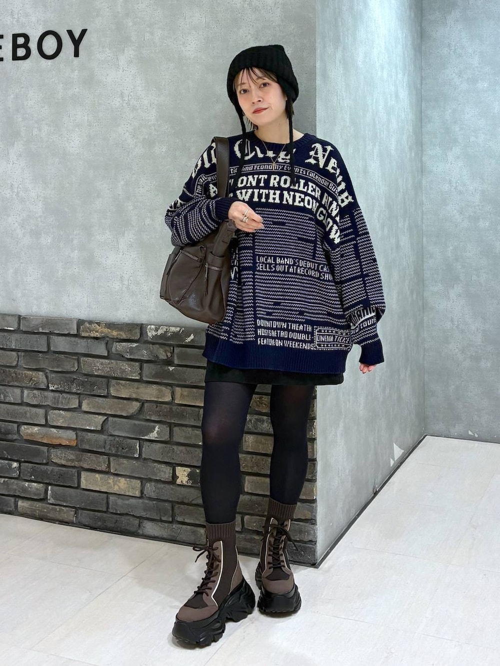 ブラウン系のブーツ、ブラウン系のボストンバッグ、ブラック系のスカートを着用したレディースの冬コーディネートの2枚目の写真