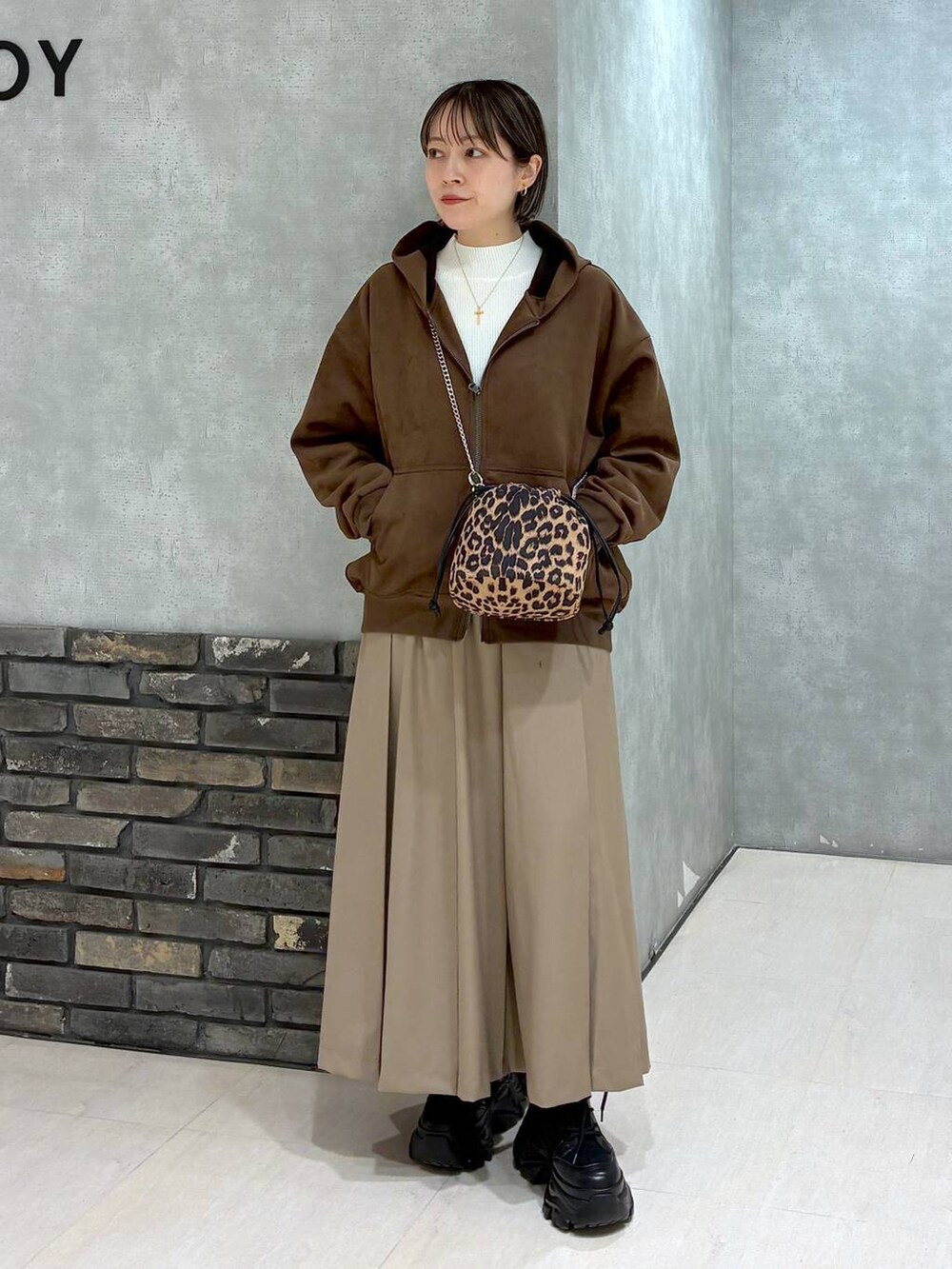 ブラック系のブーツ、ブラウン系のパーカー、ベージュ系のスカートを着用したレディースの冬コーディネートの8枚目の写真