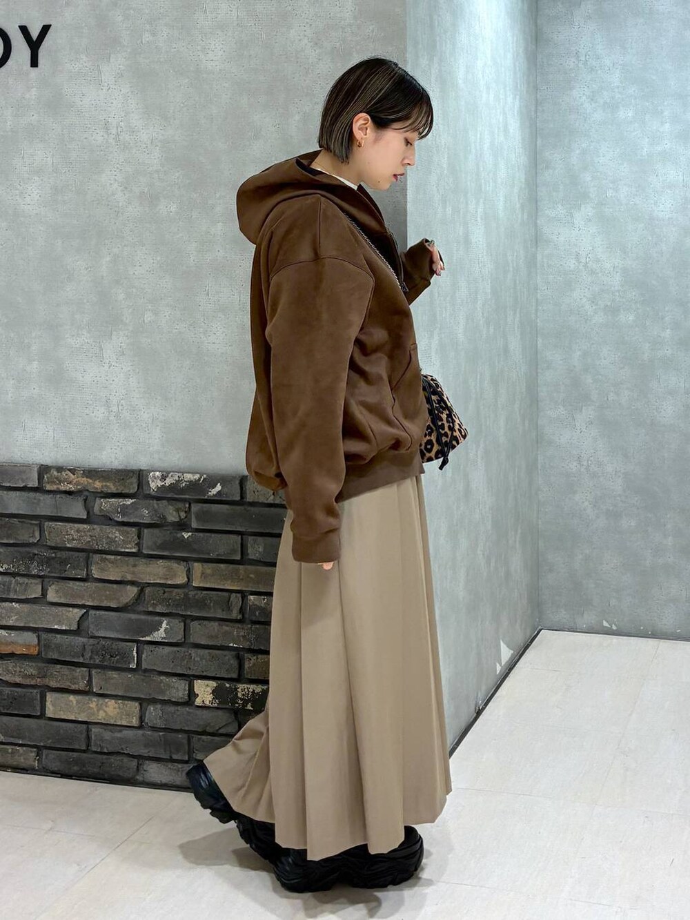 ブラック系のブーツ、ブラウン系のパーカー、ベージュ系のスカートを着用したレディースの冬コーディネートの3枚目の写真