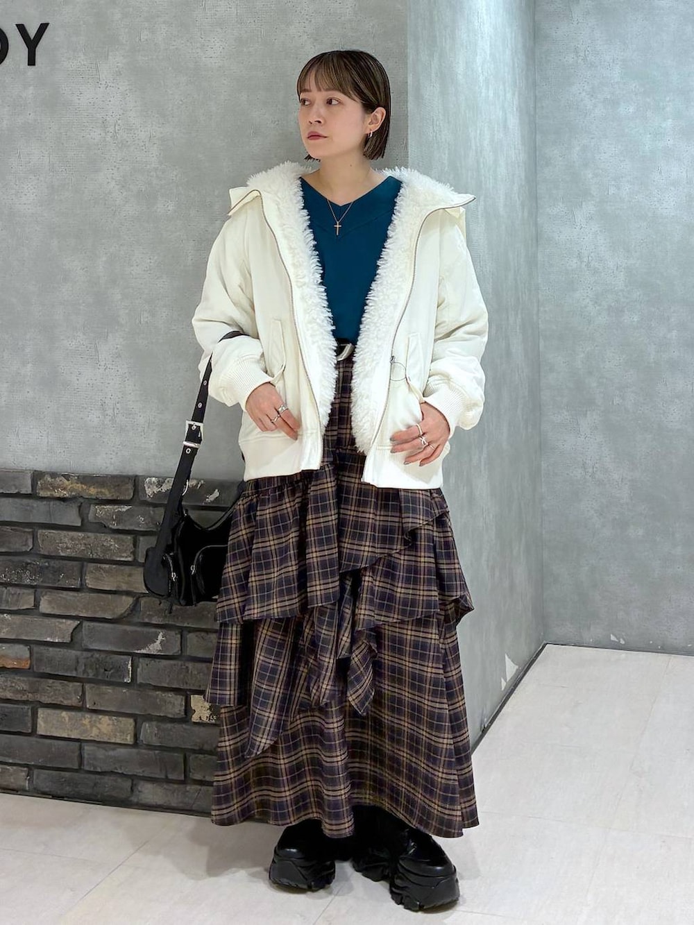 ブラック系のブーツ、ホワイト系のブルゾン、ブラウン系のスカートを着用したレディースの冬コーディネートの8枚目の写真