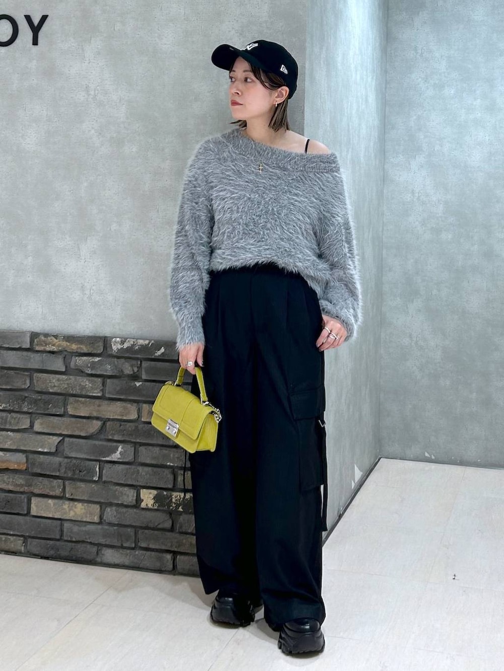 ブラック系のブーツ、イエロー系のハンドバッグ、ブラック系のスラックスを着用したレディースの秋コーディネートの6枚目の写真