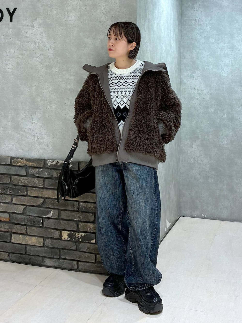 ブラック系のスニーカー、ブラウン系のブルゾン、ブラック系のショルダーバッグを着用したレディースの秋コーディネートの2枚目の写真