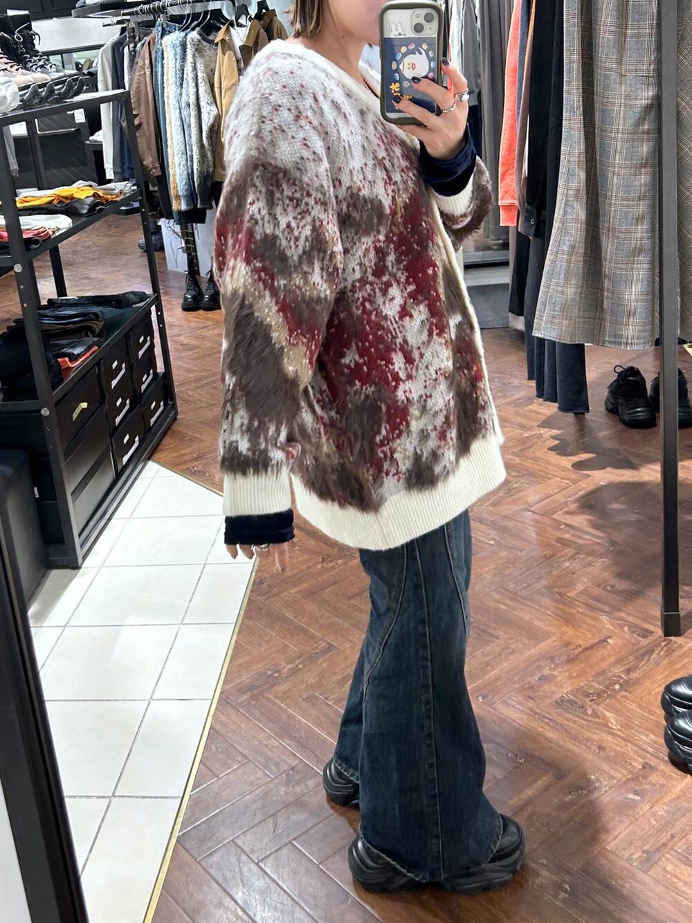 ブラック系のスニーカー、ブルー系のデニムパンツ、ホワイト系のカーディガン/ボレロを着用したレディースの秋コーディネートの5枚目の写真