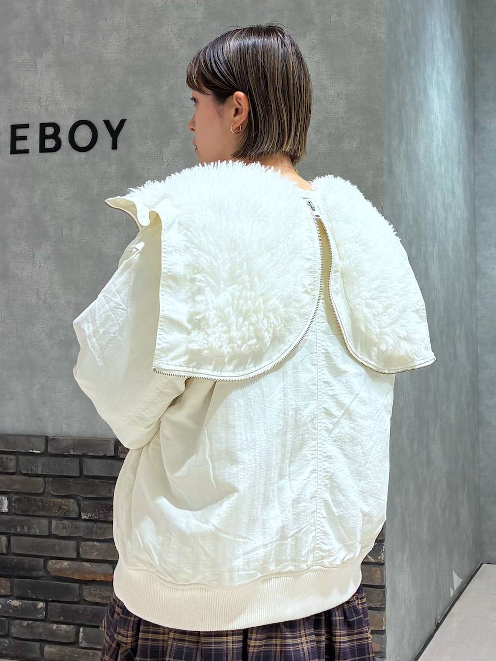 ブラック系のブーツ、ホワイト系のブルゾン、ブラウン系のスカートを着用したレディースの冬コーディネートの7枚目の写真