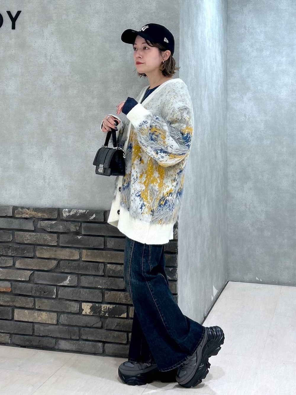 グレー系のスニーカー、ブルー系のデニムパンツ、ブラック系のハンドバッグを着用したレディースの秋コーディネートの6枚目の写真