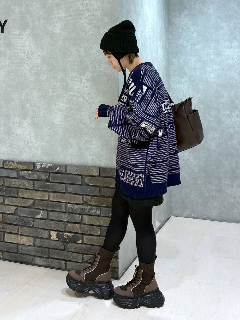 ブラウン系のブーツ、ブラウン系のボストンバッグ、ブラック系のスカートを着用したレディースの冬コーディネートの6枚目の写真