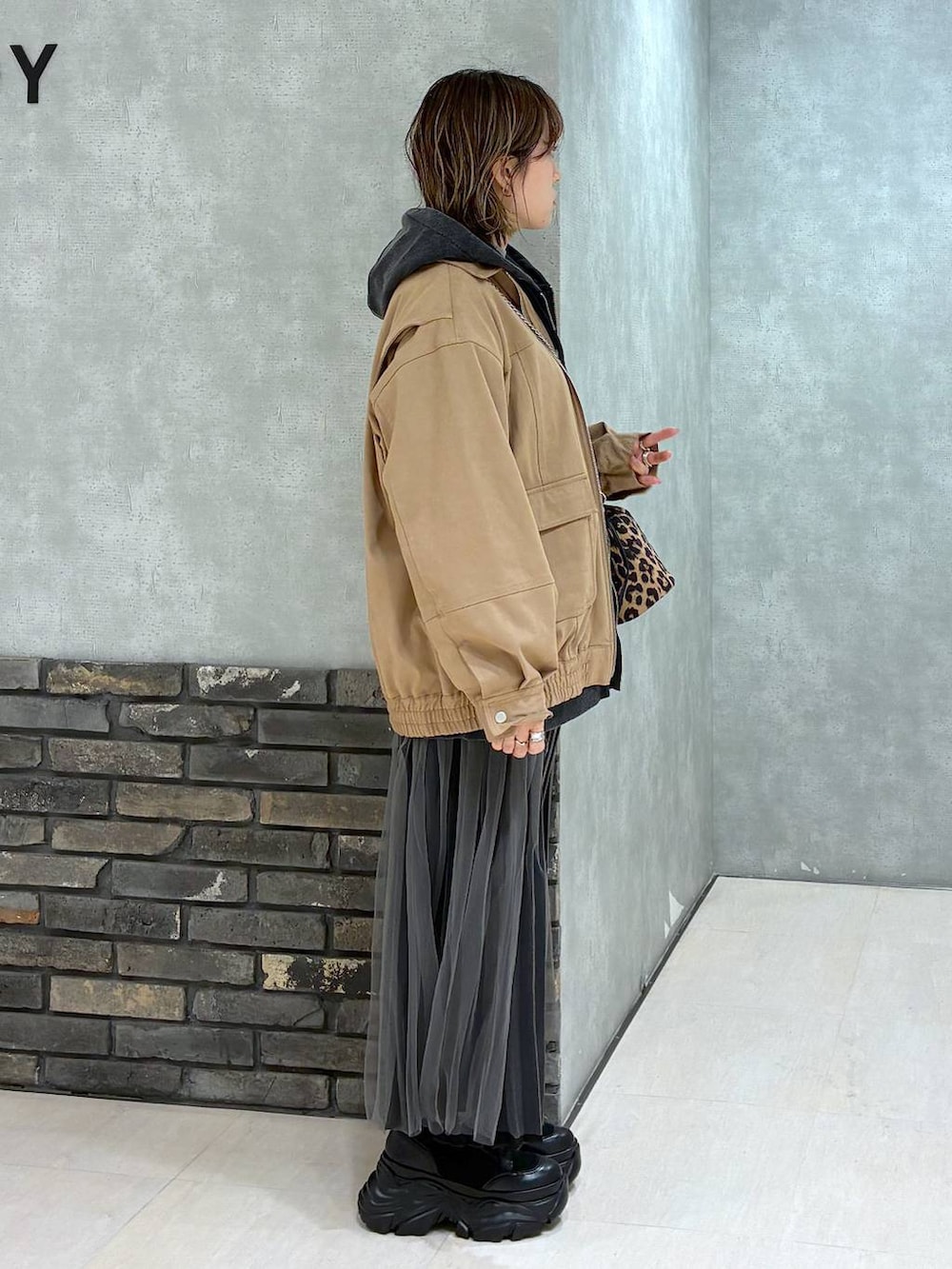 ブラック系のブーツ、イエロー系のブルゾン、ブラック系のパーカーを着用したレディースの秋コーディネートの3枚目の写真