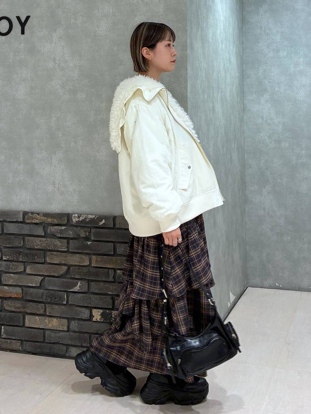 ブラック系のブーツ、ホワイト系のブルゾン、ブラウン系のスカートを着用したレディースの冬コーディネートの2枚目の写真