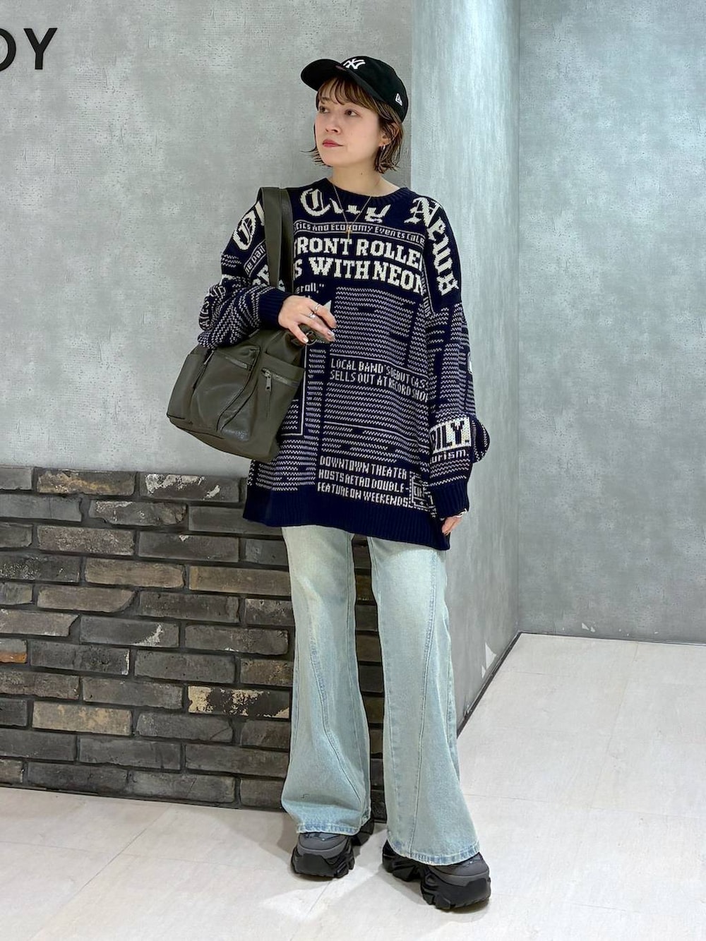 グレー系のスニーカー、ブルー系のデニムパンツ、グリーン系のボストンバッグを着用したレディースの冬コーディネートの7枚目の写真