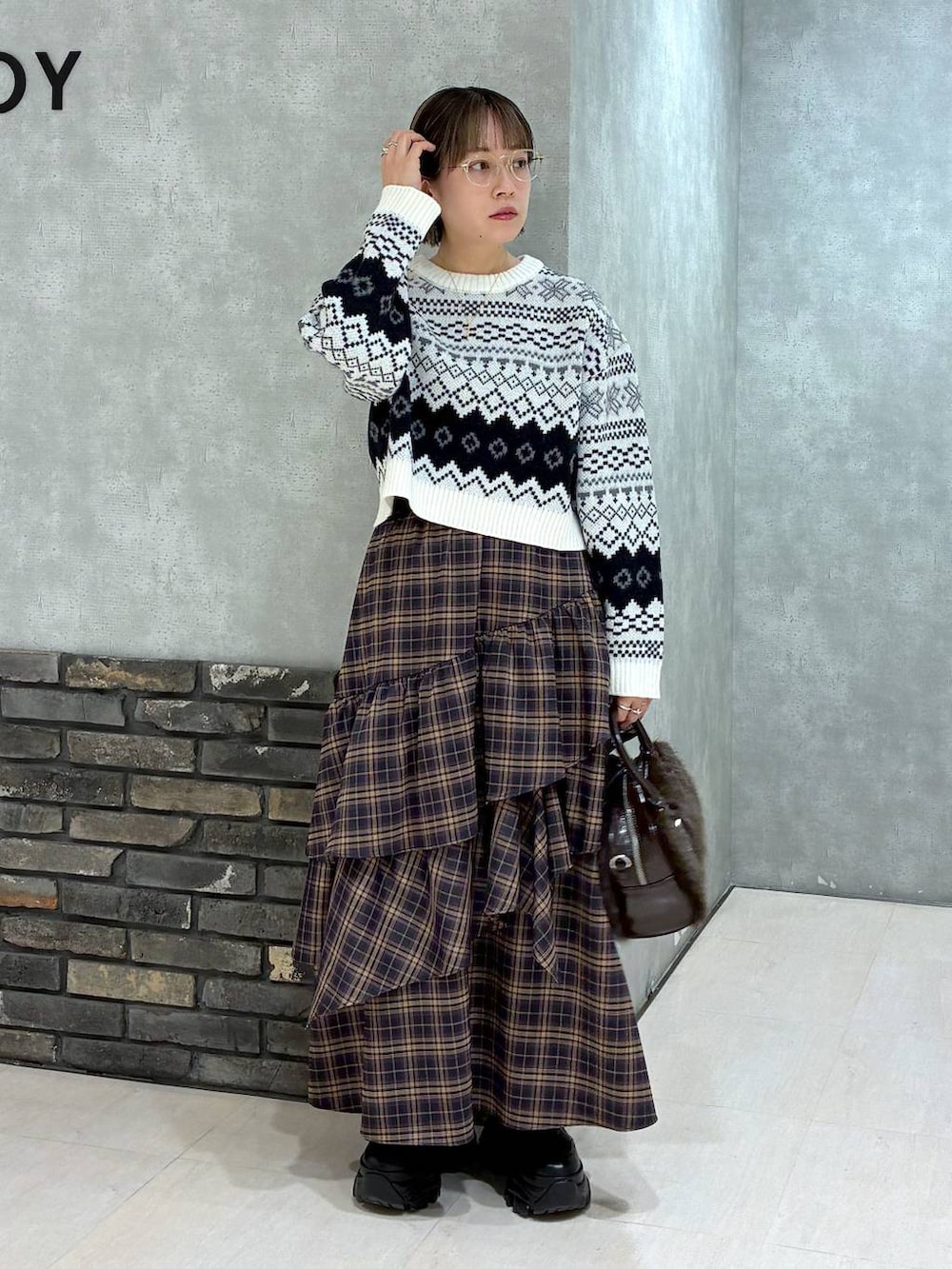 ブラック系のブーツ、ブラウン系のスカート、ブラウン系のボストンバッグを着用したレディースの冬コーディネートの7枚目の写真