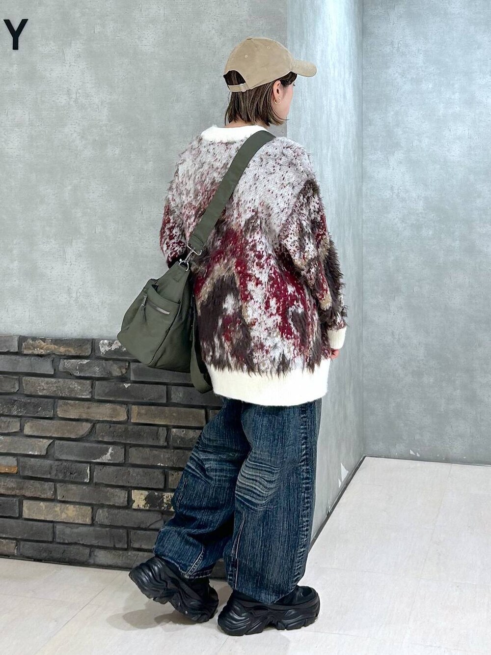 ブラック系のスニーカー、グリーン系のボストンバッグ、ホワイト系のカーディガン/ボレロを着用したレディースの秋コーディネートの3枚目の写真