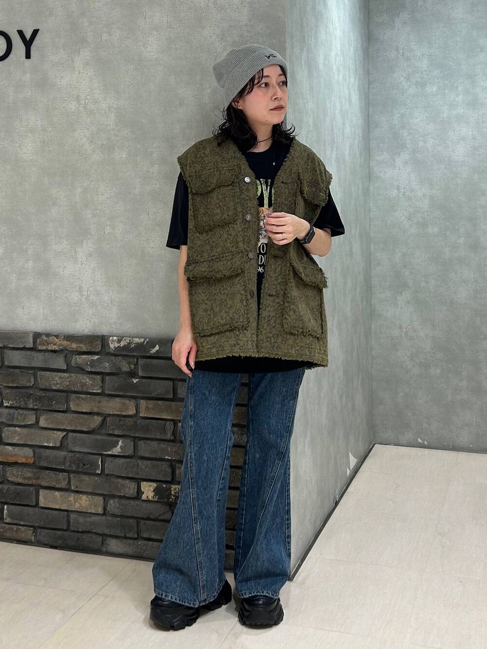 ブラック系のスニーカー、ブラック系のTシャツ/カットソー、ブルー系のデニムパンツを着用したレディースの秋コーディネートの5枚目の写真