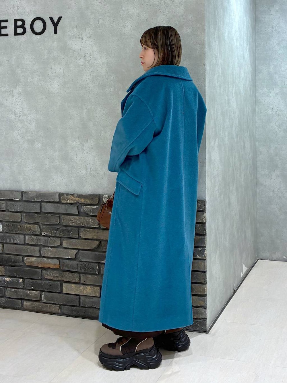 ブラウン系のブーツ、グリーン系のチェスターコート、ブラウン系のニット/セーターを着用したレディースの冬コーディネートの5枚目の写真