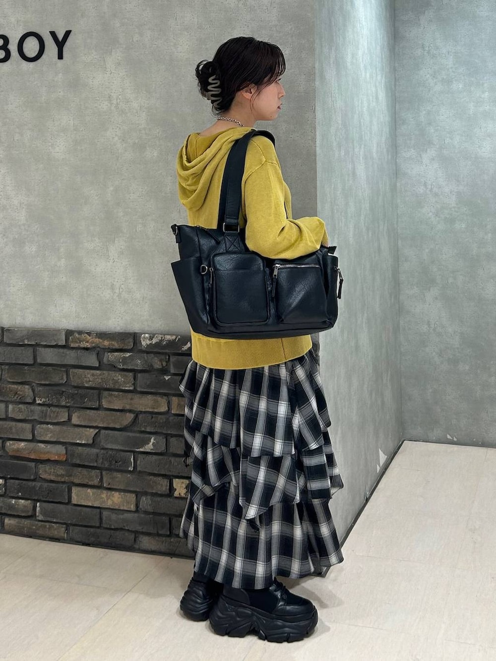 ブラック系のブーツ、ブラック系のキャミソール、ブラック系のボストンバッグを着用したレディースの秋コーディネートの3枚目の写真