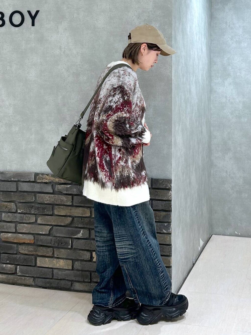 ブラック系のスニーカー、グリーン系のボストンバッグ、ホワイト系のカーディガン/ボレロを着用したレディースの秋コーディネートの2枚目の写真