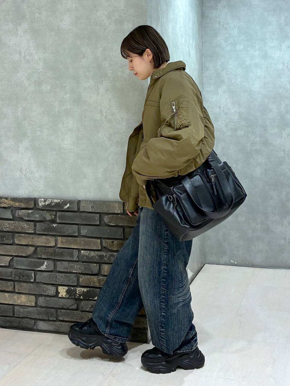 ブラック系のスニーカー、ブラック系のボストンバッグ、ブルー系のデニムパンツを着用したレディースの冬コーディネートの5枚目の写真