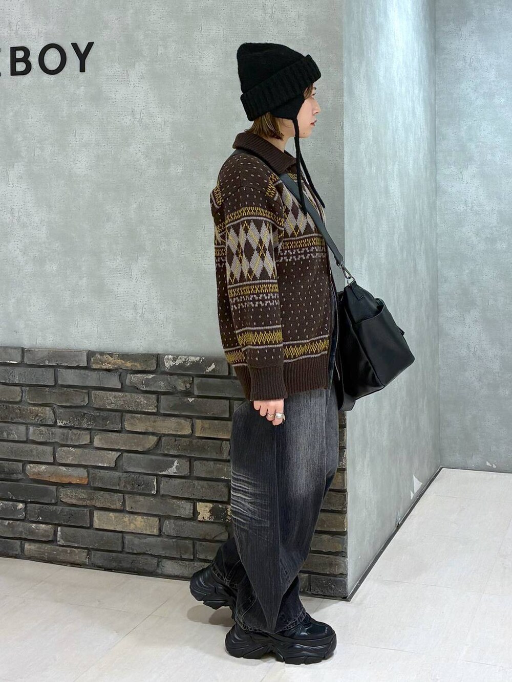 ブラック系のスニーカー、ブラック系のボストンバッグ、ブラック系のデニムパンツを着用したレディースの冬コーディネートの3枚目の写真