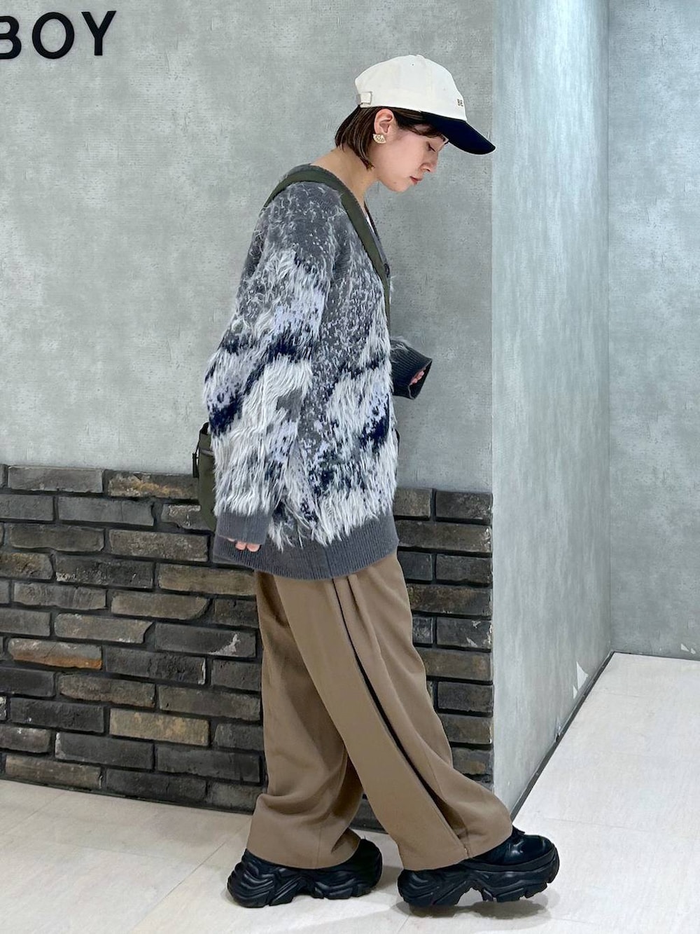 ブラック系のスニーカー、グリーン系のボストンバッグ、グレー系のカーディガン/ボレロを着用したレディースの秋コーディネートの4枚目の写真