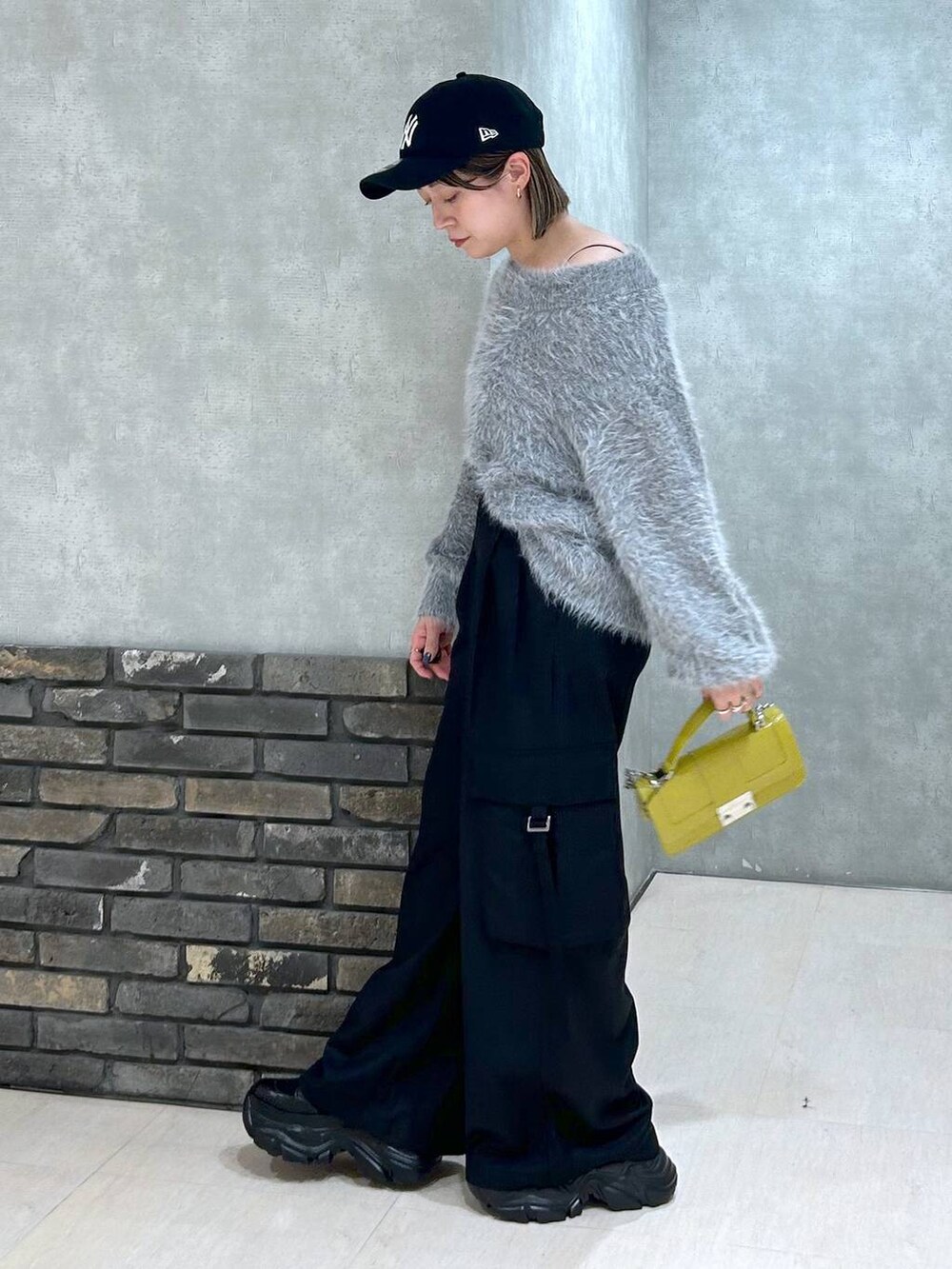 ブラック系のブーツ、イエロー系のハンドバッグ、ブラック系のスラックスを着用したレディースの秋コーディネートの4枚目の写真