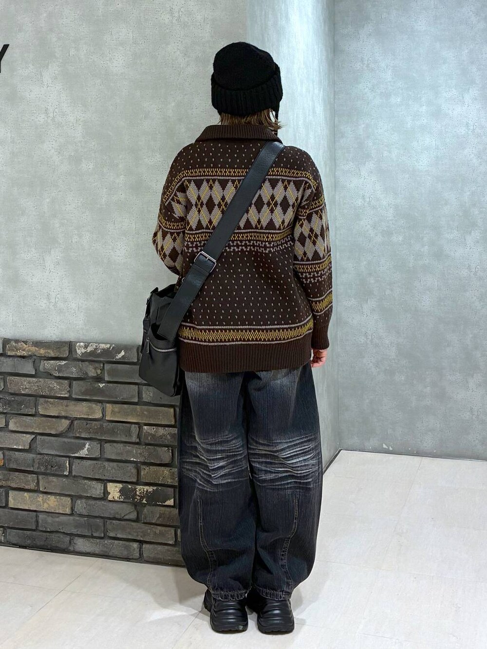 ブラック系のスニーカー、ブラック系のボストンバッグ、ブラック系のデニムパンツを着用したレディースの冬コーディネートの4枚目の写真