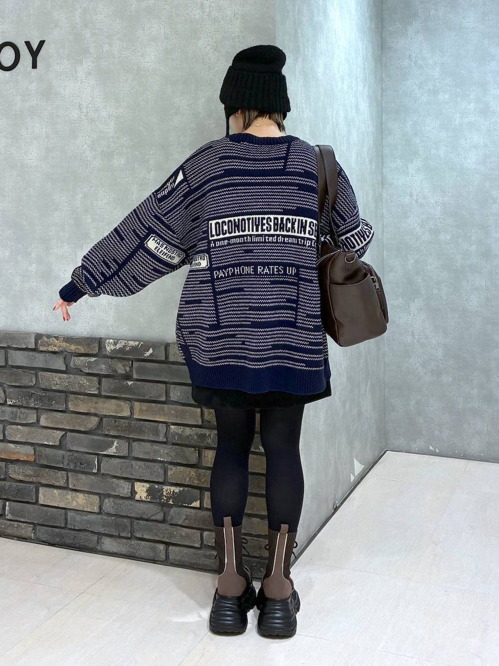 ブラウン系のブーツ、ブラウン系のボストンバッグ、ブラック系のスカートを着用したレディースの冬コーディネートの5枚目の写真