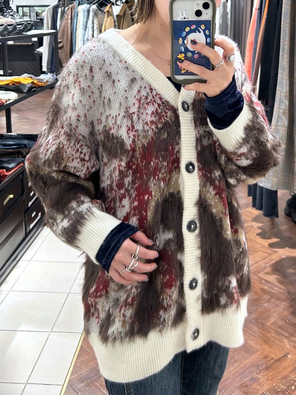 ブラック系のスニーカー、ブルー系のデニムパンツ、ホワイト系のカーディガン/ボレロを着用したレディースの秋コーディネートの2枚目の写真