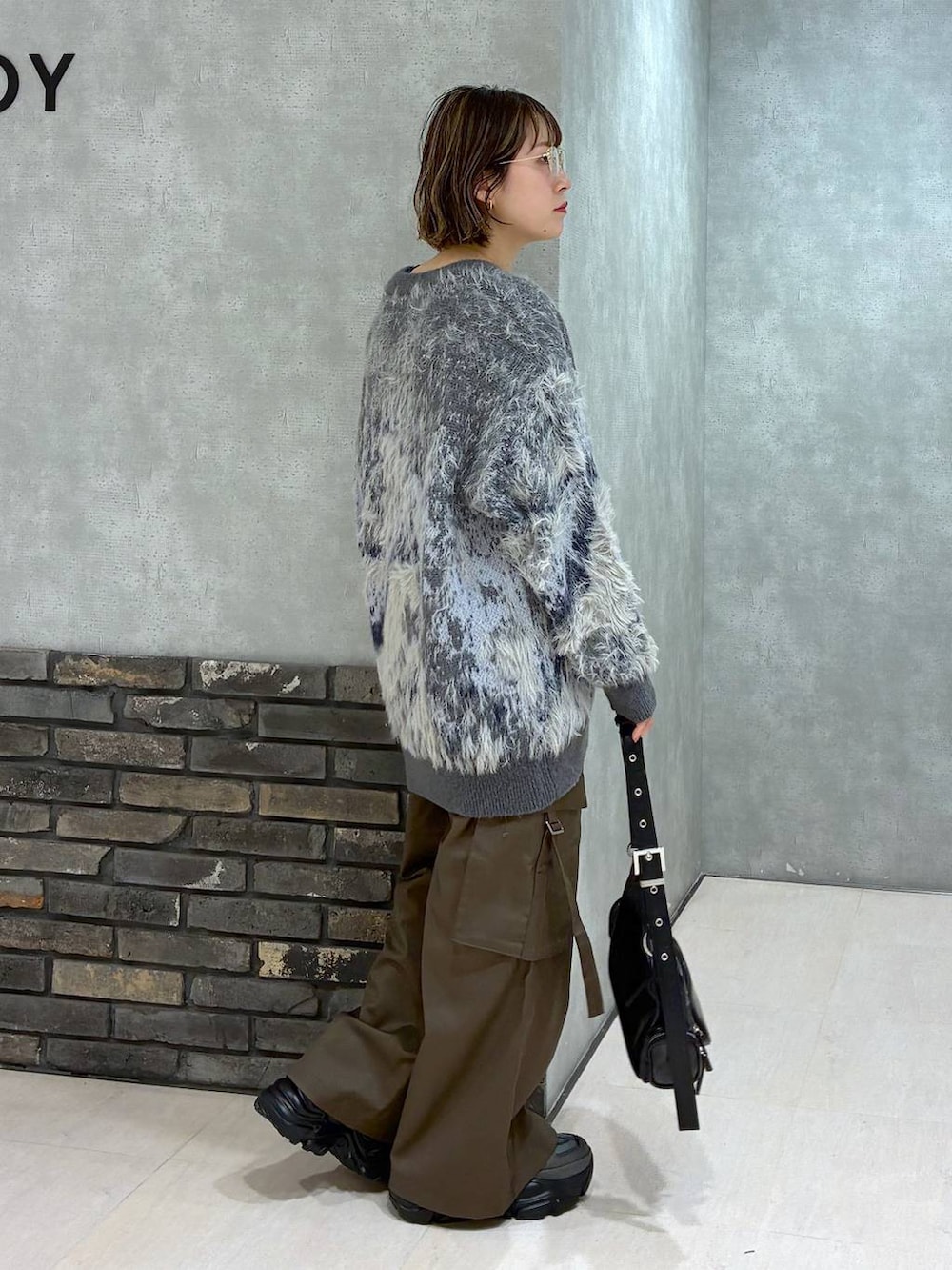 グレー系のスニーカー、ブラウン系のスラックス、グリーン系のニット/セーターを着用したレディースの冬コーディネートの2枚目の写真