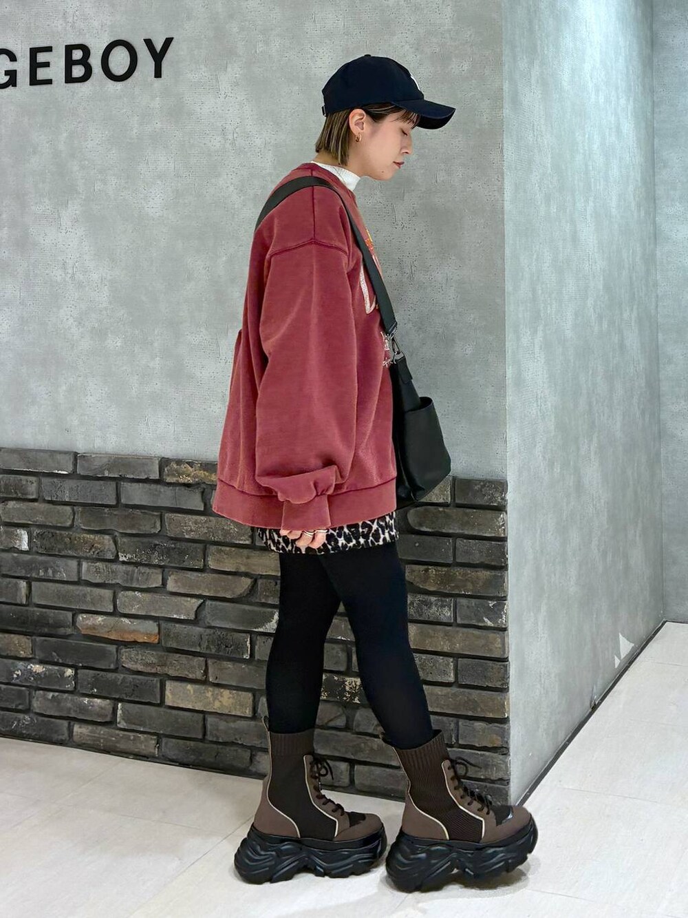 ブラウン系のブーツ、ブラック系のボストンバッグ、レッド系のスウェットを着用したレディースの冬コーディネートの4枚目の写真