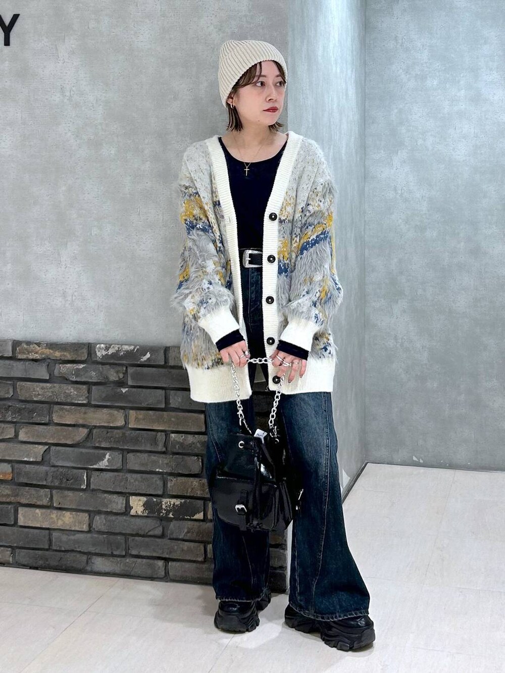 ブラック系のスニーカー、ブルー系のデニムパンツ、ブラック系のショルダーバッグを着用したレディースの秋コーディネートの2枚目の写真