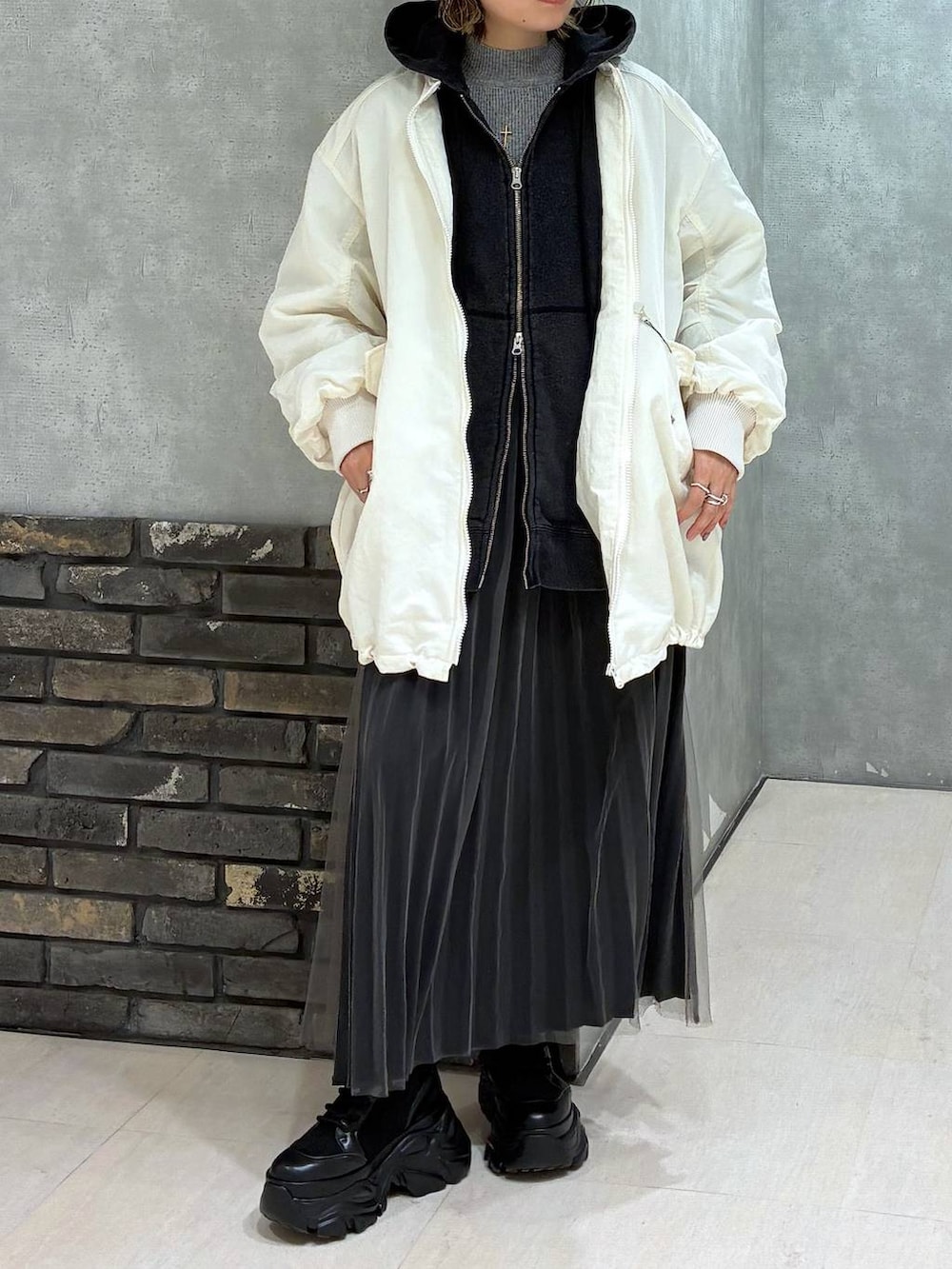 ブラック系のブーツ、ブラック系のパーカー、ホワイト系のブルゾンを着用したレディースの秋コーディネートの3枚目の写真