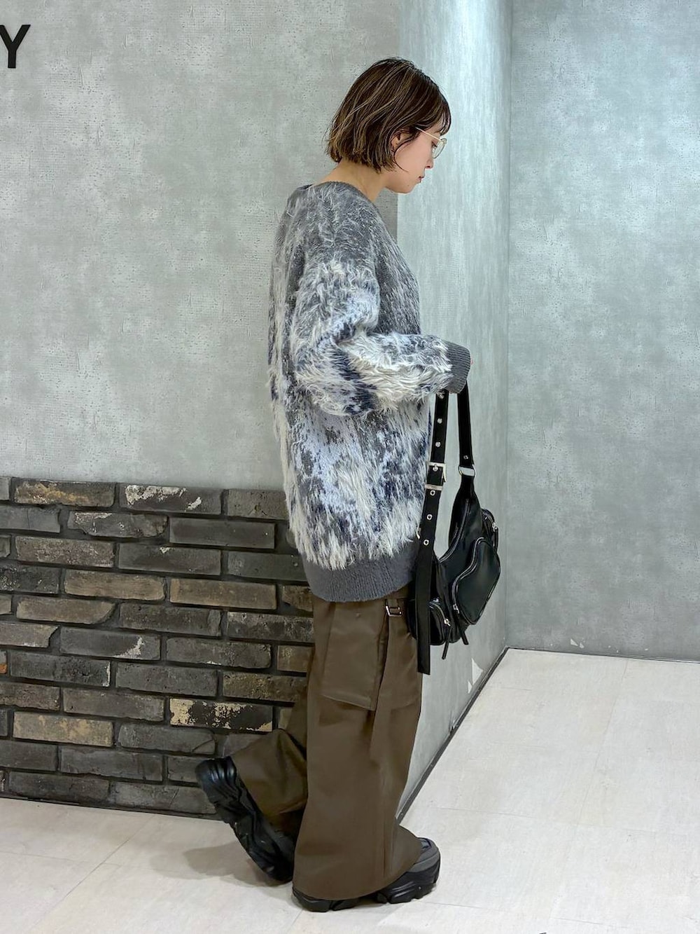 グレー系のスニーカー、ブラウン系のスラックス、グリーン系のニット/セーターを着用したレディースの冬コーディネートの3枚目の写真