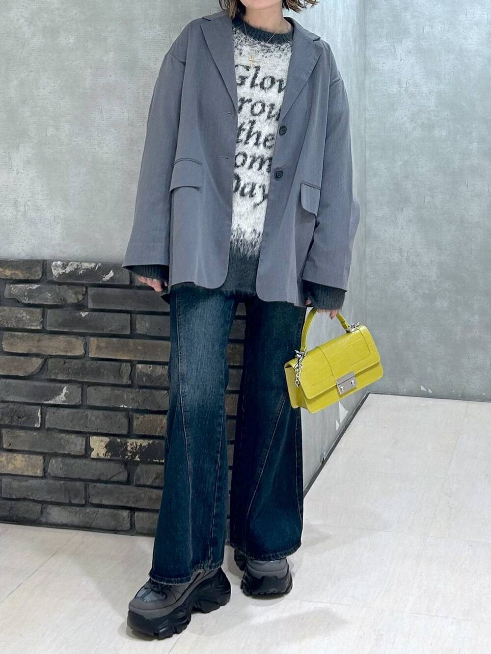 グレー系のスニーカー、ブルー系のデニムパンツ、グレー系のテーラードジャケットを着用したレディースの秋コーディネートの7枚目の写真