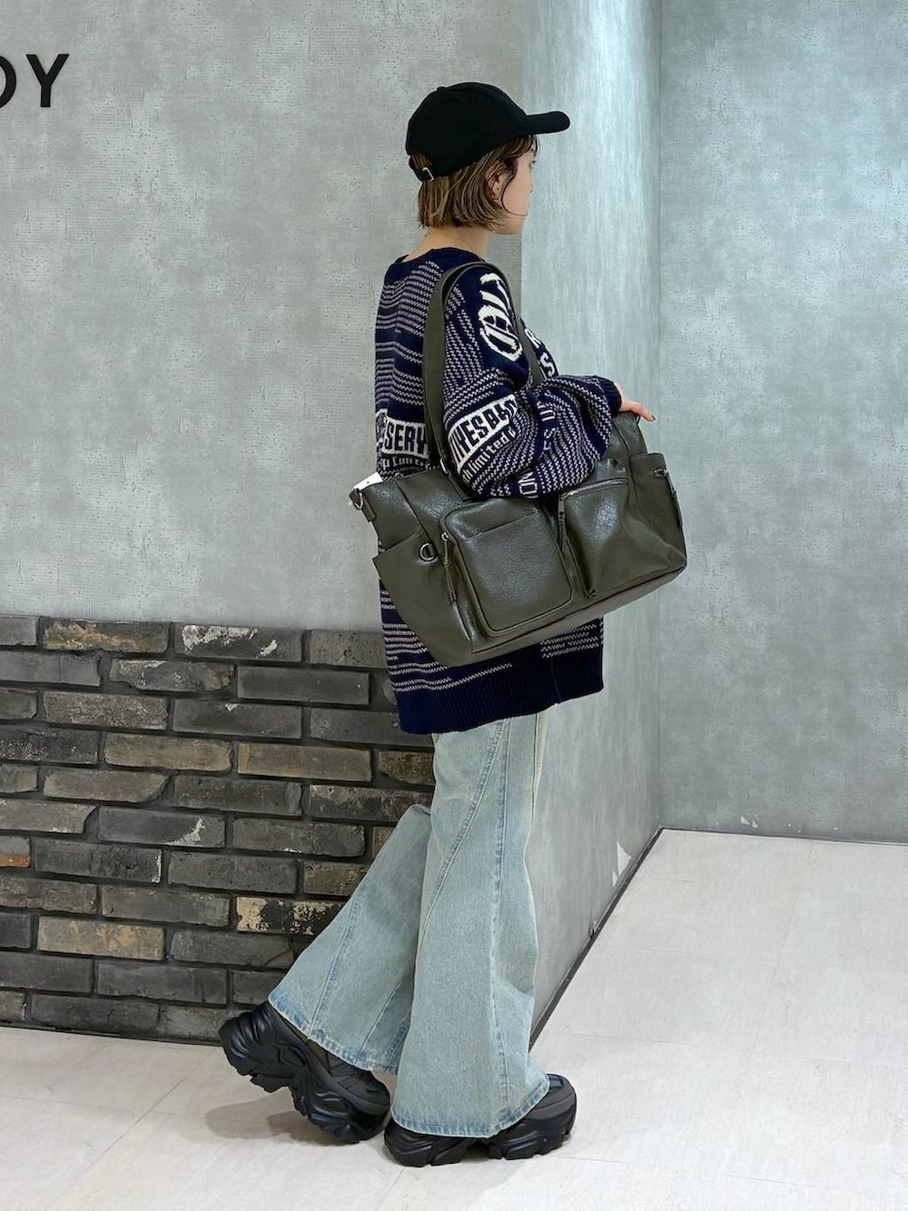 グレー系のスニーカー、ブルー系のデニムパンツ、グリーン系のボストンバッグを着用したレディースの冬コーディネートの3枚目の写真