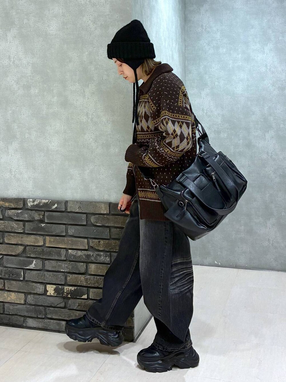 ブラック系のスニーカー、ブラック系のボストンバッグ、ブラック系のデニムパンツを着用したレディースの冬コーディネートの6枚目の写真