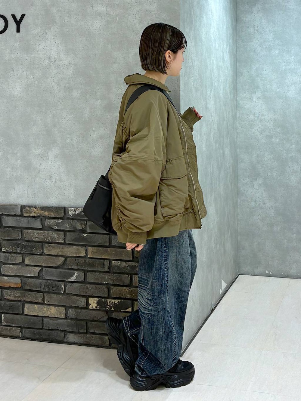 ブラック系のスニーカー、ブラック系のボストンバッグ、ブルー系のデニムパンツを着用したレディースの冬コーディネートの3枚目の写真