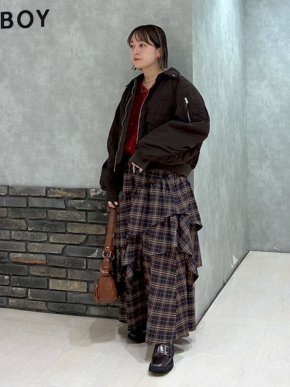 その他のブーツ、ブラウン系のスカート、ブラウン系のショルダーバッグを着用したレディースの冬コーディネートの2枚目の写真